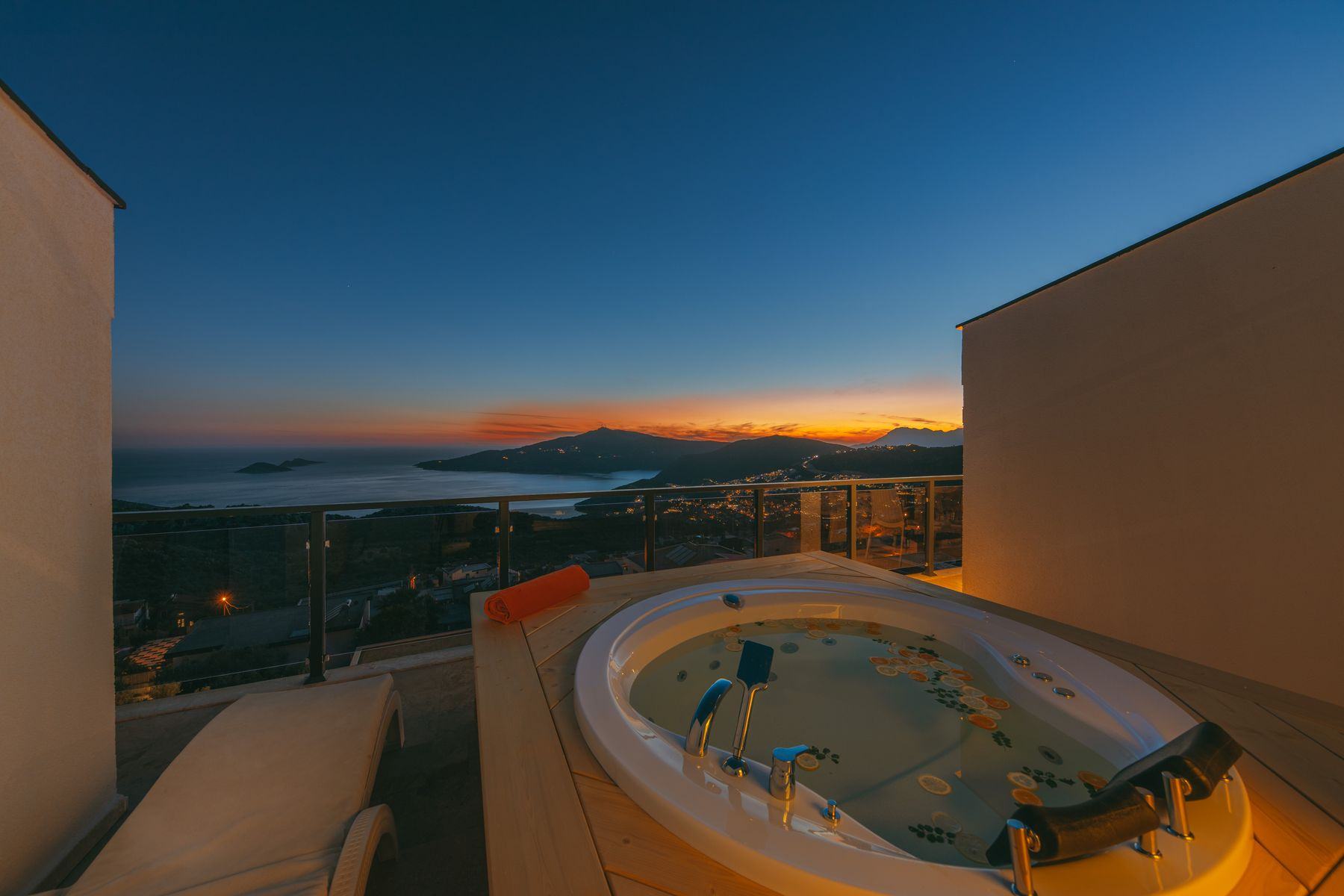 A hot tub on a terrace at dusk, overlooking the water