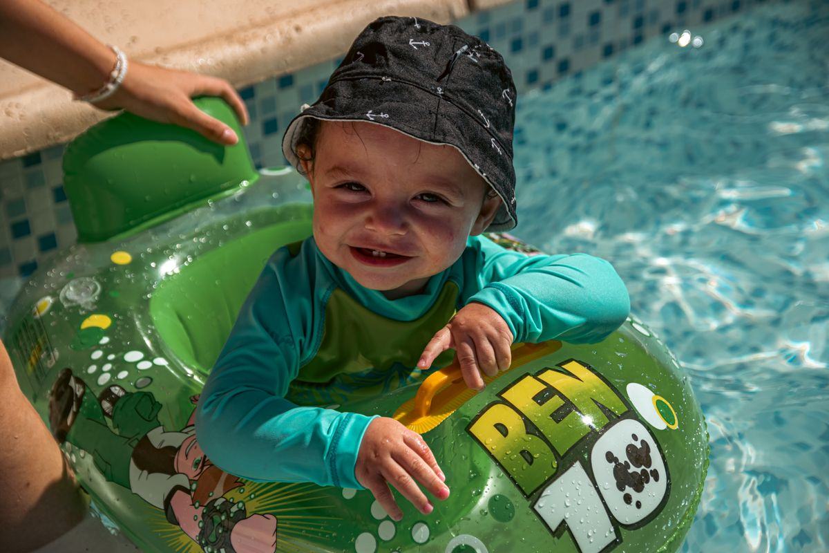 A toddler grinning in a green swim ring
