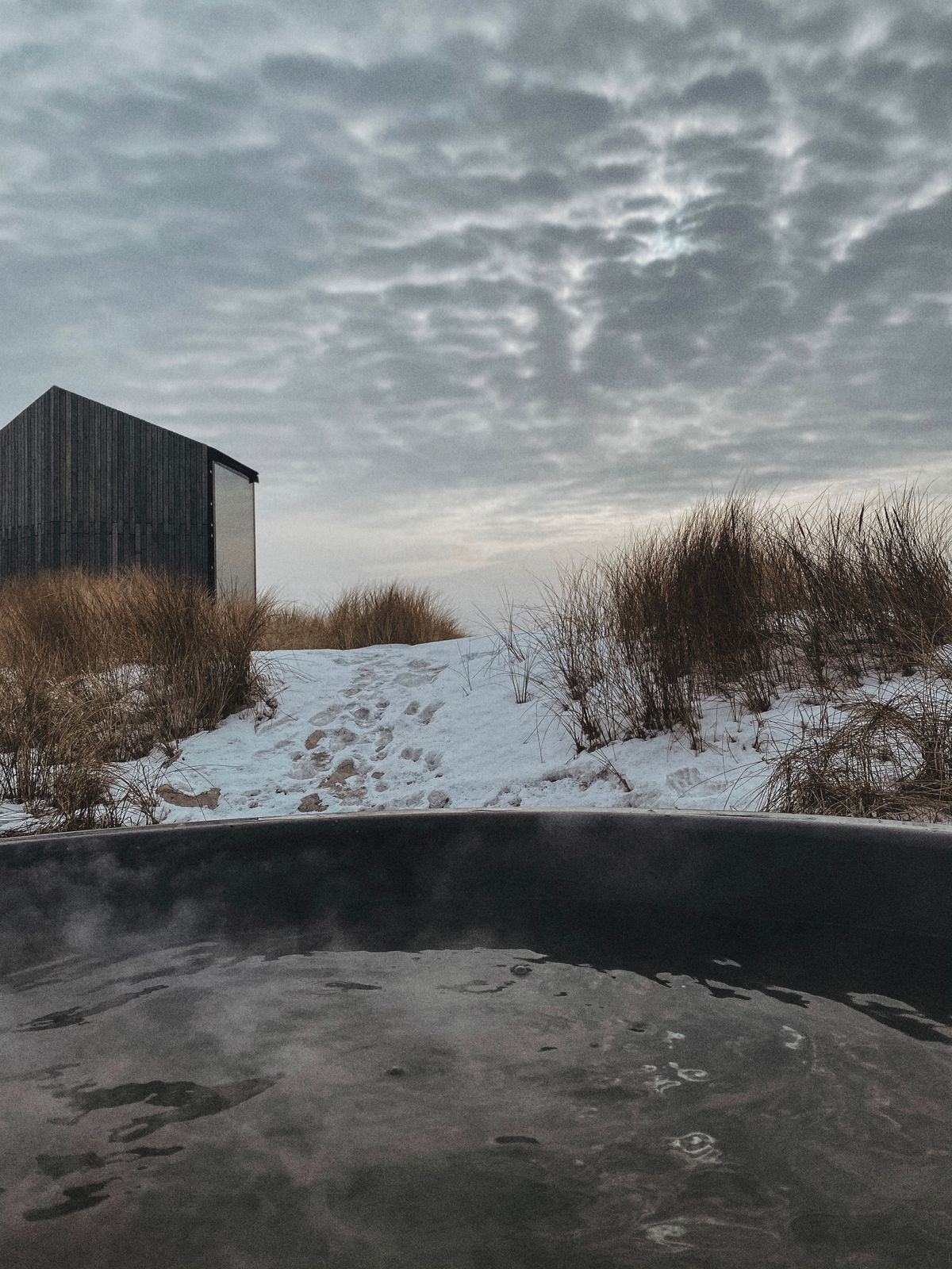 A steaming outdoor hot tub on a snowy evening